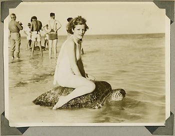 Young Woman Riding on the back of an adult Green Turtle after it has laid its eggs on the beach. This used to be a tourist attraction!!